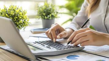 Woman Calculating Figures at Desk with Laptop and Plants photo
