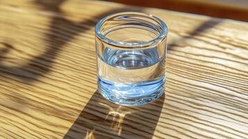 Glass of Water in Sunlight on Wooden Table photo
