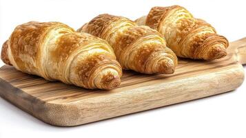 Golden brown croissants, a quintessential French pastry, sit invitingly on a rustic wooden cutting board, showcasing their flaky layers and buttery aroma These freshly baked delights promise a photo