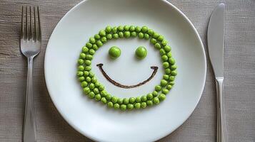 Delightful Food Art A Whimsical Smiley Face Crafted from Fresh Green Peas on a Crisp White Plate, Flanked by Elegant Silverware, Evokes Joy and Healthy Eating, Perfect for Promoting Nutritional photo