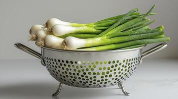 Capture the essence of fresh spring onions with this captivating image, showcasing their vibrant green shoots and pristine white bulbs nestled in a gleaming metal colander, a testament to culinary photo