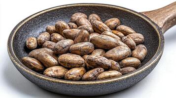 Elevate your designs with this captivating image of roasted cocoa beans in a rustic pan, perfect for culinary projects, chocolate promotions, and healthy eating blogs Explore the rich textures and photo