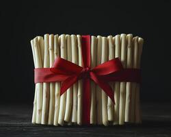 Festive Chocolate Sticks Gift Tied with a Red Ribbon Capture the essence of a delightful treat, showcasing white chocolate sticks beautifully bundled and adorned with a vibrant red ribbon Perfect for photo