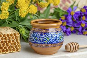 Golden Honey Pot with Fresh Honeycomb and Vibrant Flowers Capture the essence of nature's sweetness with this stunning still life A ceramic pot filled with golden honey is surrounded by a delicate photo