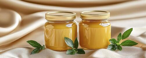Two golden jars filled with pure, natural ghee, perfect for healthy cooking and Ayurvedic wellness, elegantly presented on a soft, creamy silk backdrop with fresh green herbs, offering a visually photo