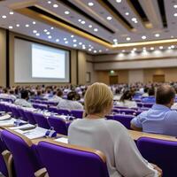 A bustling corporate seminar unfolds, its blurred background hinting at a large and attentive audience focused intently on the speaker or presentation The composition suggests a moment of shared photo