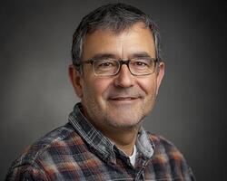 A professional headshot showcases a smiling man, set against a clean backdrop The image is designed for branding purposes, radiating approachability and confidence The subject's genuine smile and photo