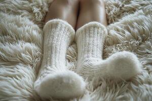 A serene scene unfolds, capturing a moment of tranquil relaxation on a chilly day The focal point rests upon a pair of plush, ivory winter socks, their soft texture inviting warmth and comfort These photo
