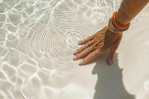 In a moment of serene reflection, a woman's hand delicately traces ephemeral patterns in the soft, yielding sand Each stroke is a meditation, a gentle dance between the physical and the ethereal The photo