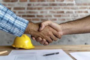 In a professional setting, two individuals engage in a handshake, signifying a business agreement or partnership The photograph's central focus is the close-up view of the hands clasped together photo
