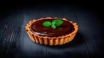 Luxurious chocolate tart elegantly decorated with a fresh mint leaf on a rustic wooden table setting photo