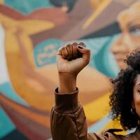 Raised fist of protester in front of colorful mural representing equality and social justice movement photo