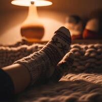Cozy winter evening resting with patterned wool socks on thick knitted rug next to warm lamp light indoors photo