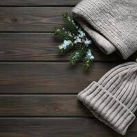 Soft beige knitted wool winter hats with snow covered pine branches on a rustic wooden background photo
