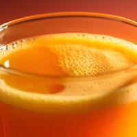 Close up of foamy orange juice in a transparent glass with soft bokeh background and fresh citrus tones photo