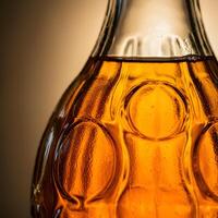 Close up of an amber glass bottle with condensation and warm backlight emphasizing texture and transparency photo