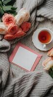 Warm cozy tea setting with delicate pink roses and empty letter with a copy space on soft knitted wool blanket photo
