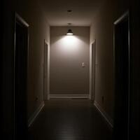 Dimly lit narrow hallway with single ceiling lamp casting moody shadows creating suspenseful atmosphere photo