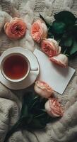 Warm cozy tea setting with delicate pink roses and empty letter with copy space on soft knitted wool blanket photo