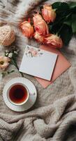 Warm cozy tea setting with delicate pink roses and empty letter with copy space on a soft knitted wool blanket photo