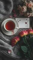 Warm cozy tea setting with delicate pink roses and an empty letter with copy space on soft knitted wool blanket photo