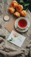 Romantic birthday tea setup with red roses a handmade card and rustic wrapped gift on soft wool blanket photo