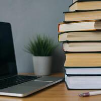Stack of books and open laptop on a wooden desk symbolizing knowledge education and learning workspace academic study research photo