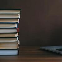 Stack of books and open laptop on wooden desk symbolizing knowledge education and learning workspace academic study research photo