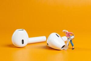 A tiny figurine of a woman appears to clean an oversized earbud photo