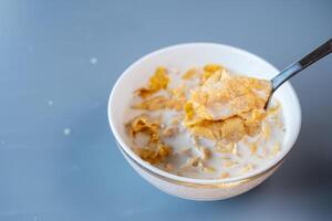 Spoon lifting a portion of crispy cornflakes soaked in milk from a bowl photo