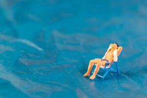 Man lounges on a beach chair, enjoying a peaceful moment on a textured blue surface resembling water photo