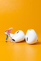 A tiny figurine of woman appears to clean an oversized earbud photo