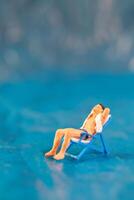 A man lounges on a beach chair, enjoying a peaceful moment on a blue surface resembling water photo