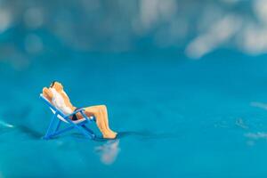 A man lounges on a beach chair, enjoying a peaceful moment on a textured blue surface resembling water photo