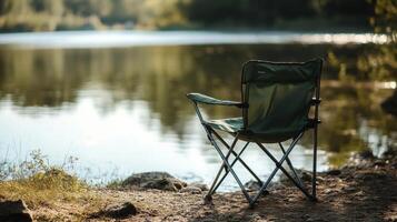 Empty green camping chair by a serene lake in sunlit forest setting photo