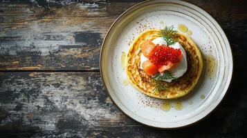 Gourmet blini with smoked salmon, sour cream, and roe on rustic plate photo