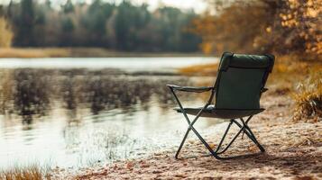 Solitary camping chair by tranquil autumn lakeside in forest setting photo
