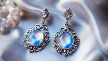 Elegant silver earrings with moonstone gemstone on luxurious satin fabric photo