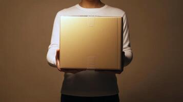 Young adult holding box in hands against minimalist background photo