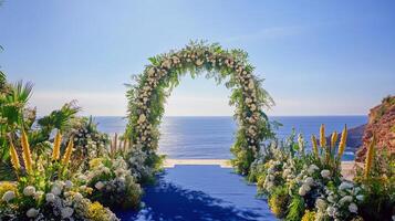 Beautiful floral wedding arch by ocean with blue sky and greenery photo