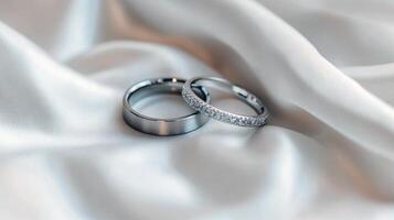 Two elegant silver wedding rings on luxurious white satin fabric photo