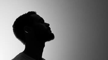 Silhouette of african male adult with beard in profile view against gradient background photo