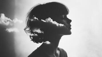 Silhouette of young female with clouds in artistic double exposure photo