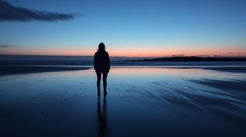 Silhouette of a female at sunset beach with reflective ocean views photo