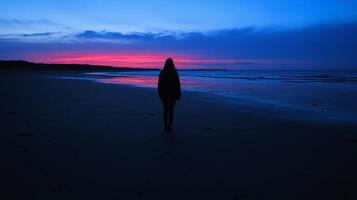 Silhouette of woman on beach at sunrise with vibrant sky photo