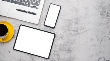 Office desk workplace with blank screen tablet and smart phone, laptop, pen and cup of coffee, Top view flat lay with copy space. photo