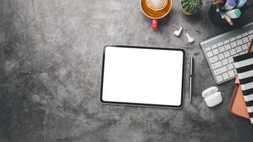 Office desk workplace with blank screen digital tablet, earphone, keyboard computer, notebook and cup of coffee, Top view flat lay with copy space. photo
