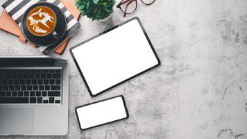 Modern office desk workplace with blank screen digital tablet and smartphone, laptop, eyeglass, notebook and cup of coffee, Top view flat lay with copy space. photo