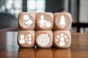 Wooden blocks with icons symbolizing commitment, teamwork, and success, arranged on a wooden table. photo