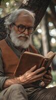 Elderly man reading a book under a tree, close-up of thoughtful senior with glasses and white beard, peaceful outdoor setting, wisdom and solitude, autumn afternoon, reflective older adult. photo